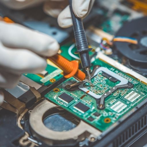 Technician repairing a laptop motherboard in a modern lab